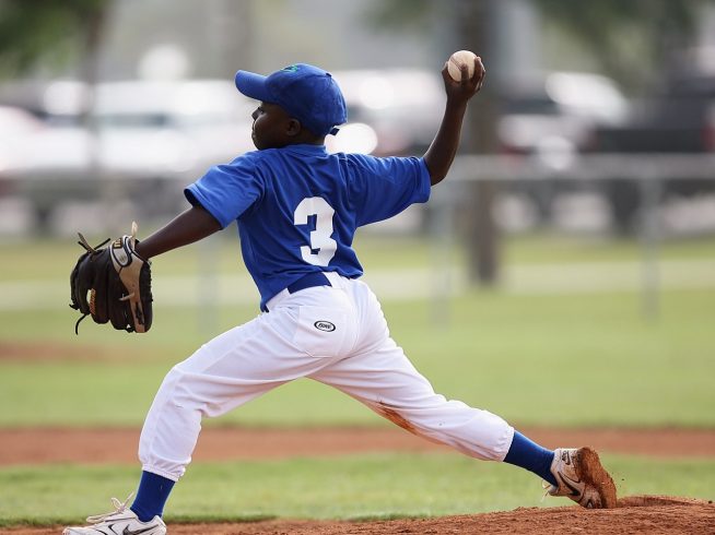 boy pitching baseball during active game