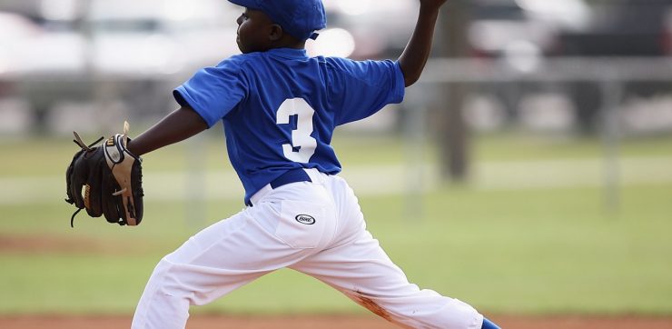 boy pitching baseball during active game