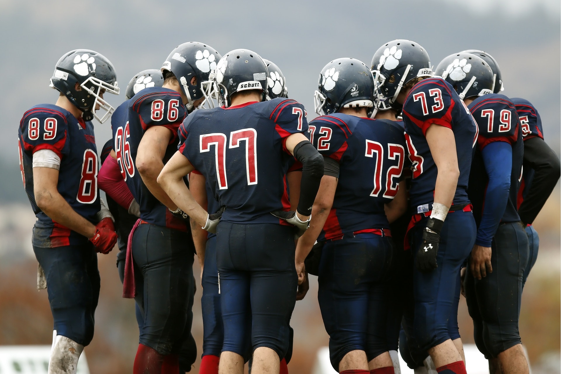 group of highschool football players standing in a huddle