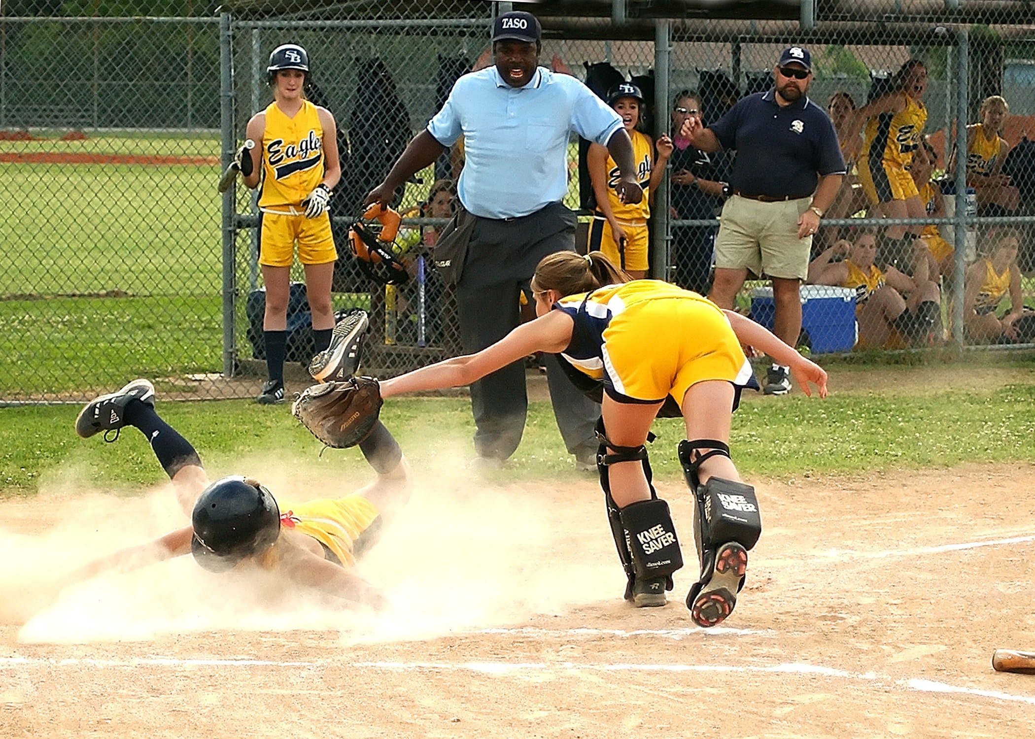 girls playing softball with ref sliding actively