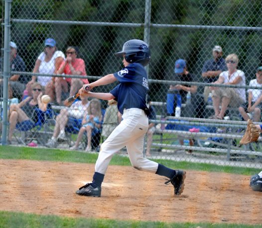 young child hitting the ball at a baseball game