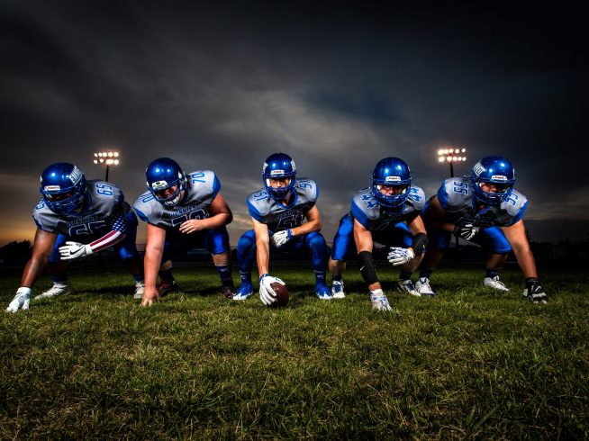 high school football with blue jersey in stance