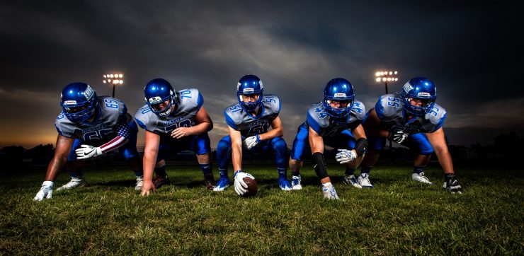 high school football with blue jersey in stance