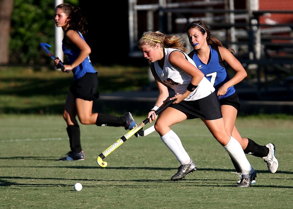 field hockey game at highschool with 2 women running