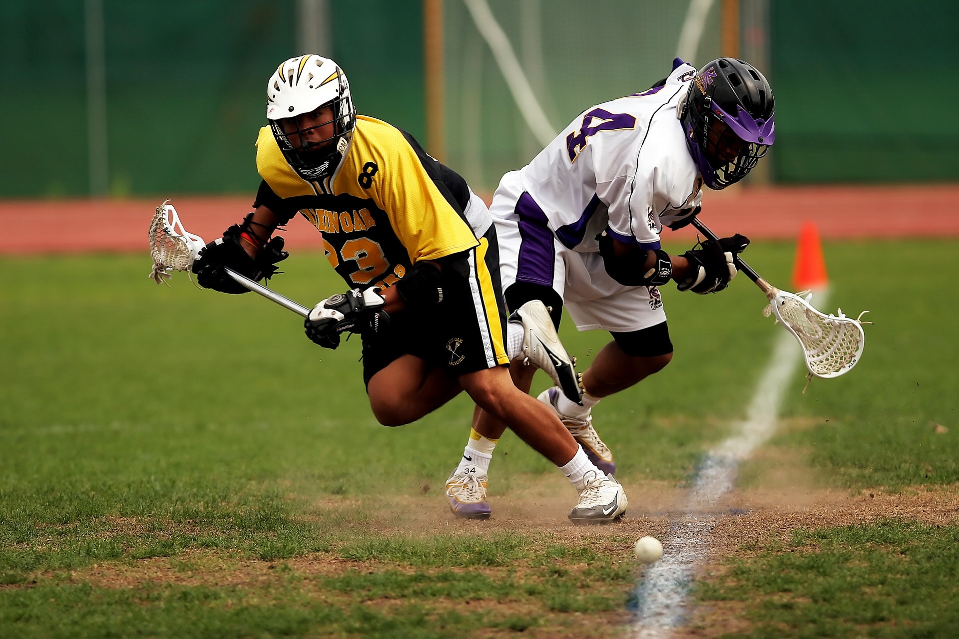 2 men playing lacrosse in a field action