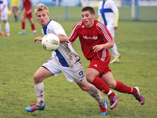 2 high school boys running playing soccer